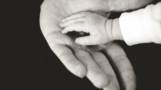 Äldres hand håller babyhand
