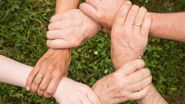 Olika generationer som håller händerna i ring så bara händerna syns och knyter dem samman