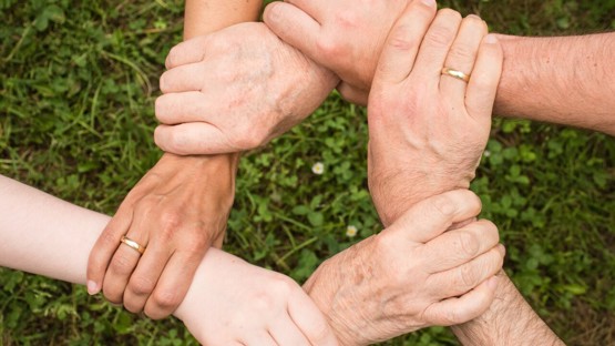 Olika generationer som håller händerna i ring så bara händerna syns och knyter dem samman