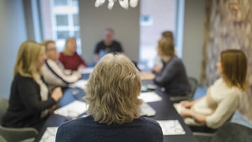 Personer i möte vid ett konferensbord.