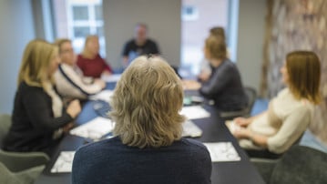 Personer i möte vid ett konferensbord.