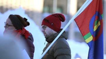 Bild på en person som håller samernas flagga på Samisk nationaldag 2019 på Umeå universitet