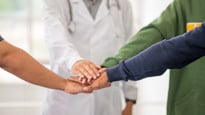 Samarbete, grupp med händer på varandra varav en läkares hand.