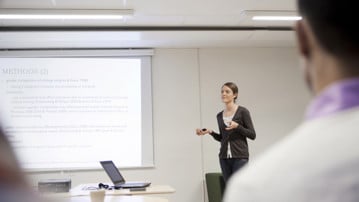 A young woman presenting a text in front of a audience