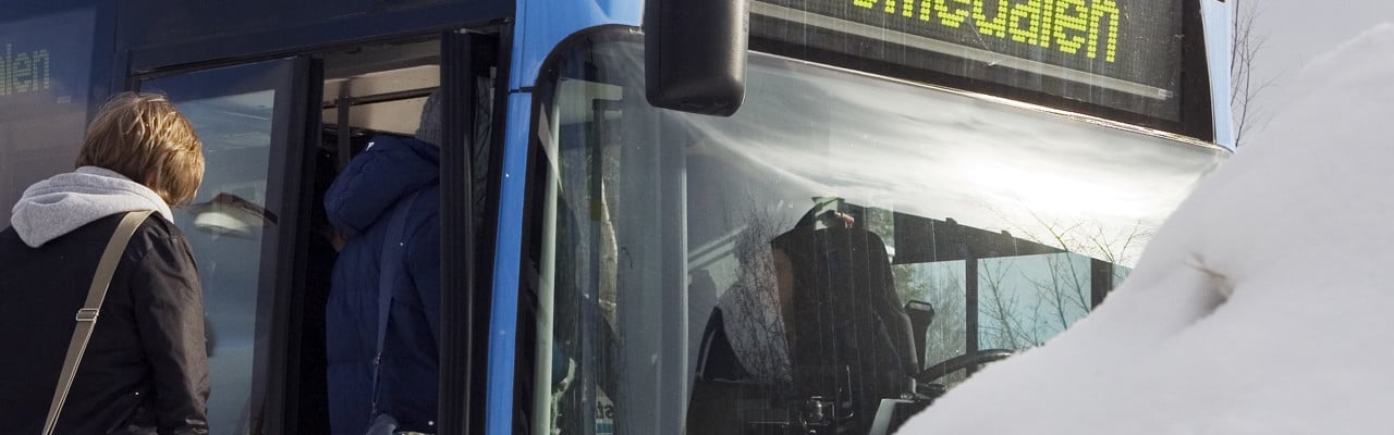 Studenter kliver på en buss som avgår vid Campus. Bredvid en stor snödriva.