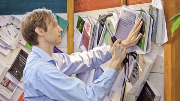 Doktorand spikar upp sin doktorsavhandling på anslagstavlan i Universitetsbiblioteket.