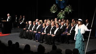 Studentmarskalkar står på scenen vid Årshögtidens ceremoni.