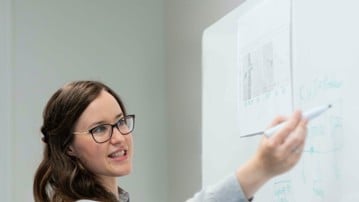 Två personer står framför en white board