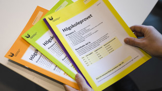 En hand håller ett antal högskoleprov.